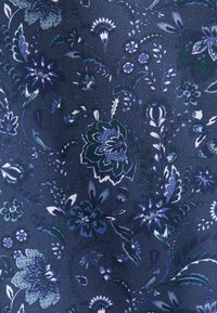 Tissu bleu avec un motif floral sombre dans des nuances de bleu, noir et blanc, comprenant différentes fleurs et des feuilles délicates.