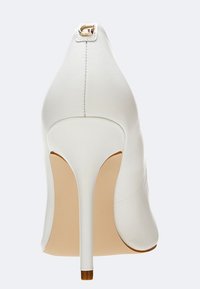 Escarpin blanc à talon haut avec un bout pointu, tige en cuir lisse et accent métallique à l'arrière. Le talon est fin et effilé.