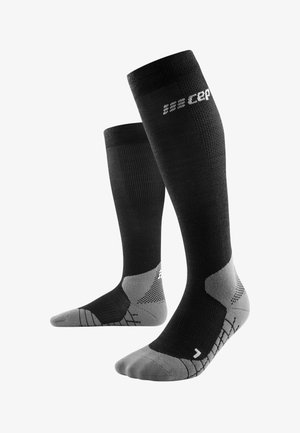 Chaussettes de compression noires jusqu'aux genoux avec des accents gris, présentant un design texturé et un renfort aux orteils et au talon pour plus de durabilité.
