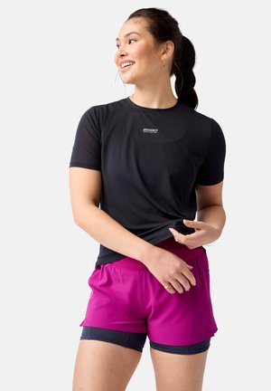 T-shirt de sport à manches courtes noir en tissu texturé avec logo "Brooks", associé à un short rose vif avec une taille élastique.