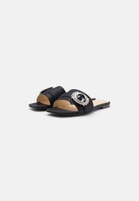 I sandali in satin nero presentano una fascia larga con una fibbia decorativa in argento adornata con strass trasparenti, una suola piatta e un design open toe.