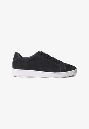 Black suede sneakers with a smooth texture, rounded toe, white rubber sole, and six lace eyelets. Minimalistic design with subtle stitching.
