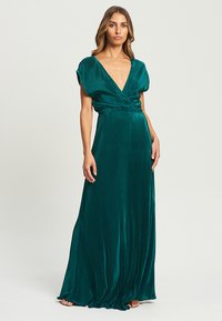 Robe maxi vert émeraude avec un décolleté en V profond, des manches courtes bouffantes et une taille cintrée. Des plis texturés créent un élégance fluide.