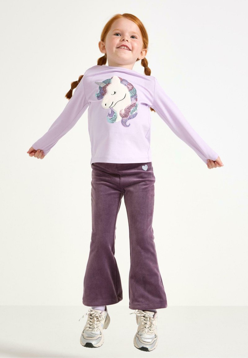 Chemise lilas à manches longues avec un design de licorne en sequins, associée à un pantalon évasé violet en tissu doux. Cœur détaillé sur le pantalon.