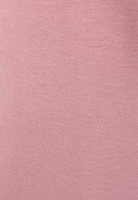 Tessuto rosa chiaro con una texture liscia e una fine rigatura, che mostra lievi variazioni di colore e una consistenza uniforme di elasticità su tutta la superficie.