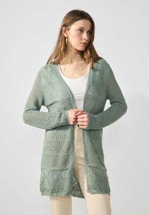 Hellgrüner offenen Strickcardigan mit strukturiertem Design und geometrischen Mustern. Lange Ärmel und Taschen runden das Gesamtbild ab.