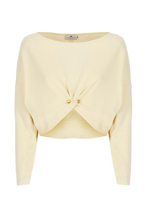 Top giallo corto realizzato in tessuto liscio, con scollo a barca, maniche lunghe e un dettaglio frontale intrecciato accentuato da hardware dorato.