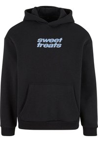 Black hoodie made of soft material, featuring a front pocket and blue text saying "sweet treats" across the chest.