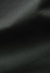 Tissu noir avec une texture lisse et légèrement brillante, affichant un motif à fines côtes, plié pour montrer la profondeur et la dimension à la lumière.