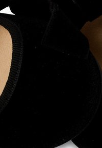 Zapato plano de terciopelo negro con punta redondeada, que cuenta con una planta interna suave y un exterior texturizado. Diseño simple con acentos de hardware mínimos.