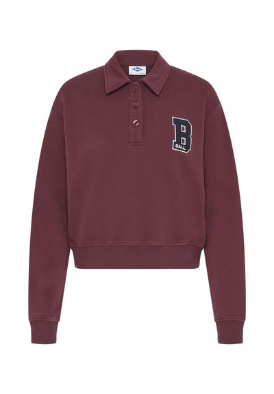 Burgundy színű, rövidített pólópulóver gallérral, három gombos gombolással és kontrasztos hímzett "B BALL" logóval a mellrészen. Puha textúra.