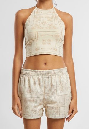 Kermanvärinen halterneck-lyhyt toppi paisley-kuviolla, yhdistetty samansuunnikkaisiin shortseihin, joissa on samanlainen kuvio ja joustava vyötärönauha.