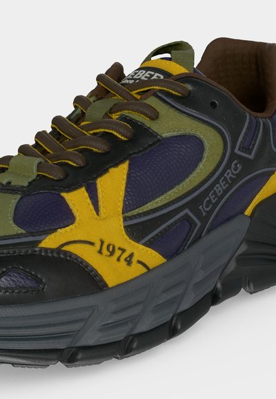 Basket épaisse avec des panneaux jaunes, vert olive, noir et violet, des lacets marron, un détail "1974" et un marquage "Iceberg" sur le côté.