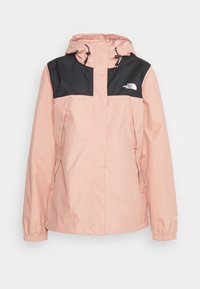 Veste imperméable rose clair avec panneau noir sur la poitrine, capuche ajustable, poignets élastiques et logo brodé sur le côté gauche supérieur.