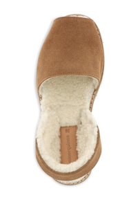 Chaussure en daim marron à enfiler avec un bout arrondi et une doublure en peau de mouton. Semelle légèrement texturée avec une finition naturelle et bords cousus.