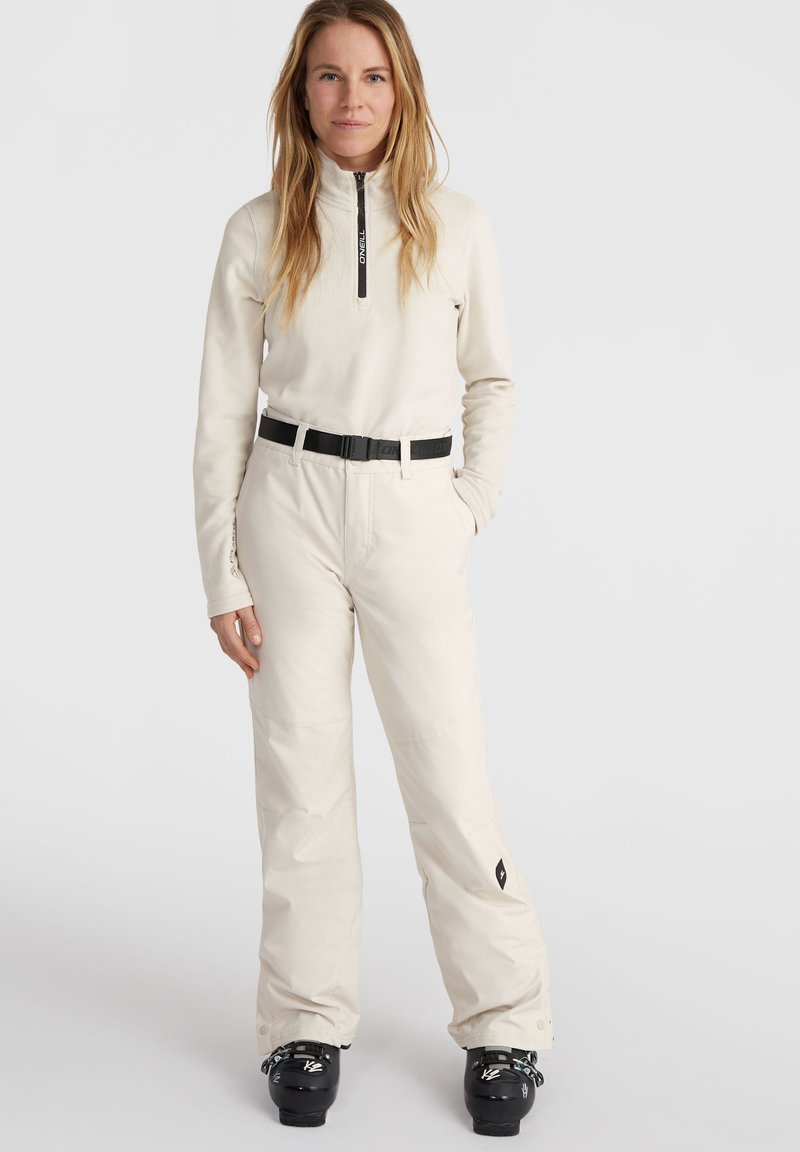 Sudadera de forro polar de color claro con cuello de media cremallera y mangas largas, combinada con pantalones de nieve beige que presentan un cinturón negro y acentos de logo.