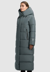 Cappotto lungo grigio imbottito con colletto alto, dotato di tasche frontali con zip, taglio dritto e finitura liscia e opaca.