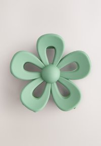 Pince à cheveux en forme de fleur vert menthe avec cinq pétales, bouton central arrondi et espaces découpés, présentant une finition mate.