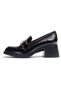 Mocasín de charol negro con punta cuadrada, tacón bajo en bloque y acento de hebilla metálica en la parte frontal. Textura suave y diseño elegante.