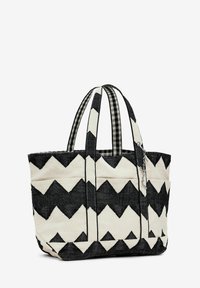 Tote bag made of black and white woven fabric featuring a zigzag pattern. It has dual striped handles and a checked interior lining.