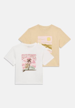 Dos camisetas: una blanca con el texto "BUENOS MOMENTOS" y un gráfico de palmera, y la otra beige con una impresión de sol y paisaje en colores pastel.
