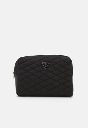 Zwarte gewatteerde cosmeticatas met een driehoekig logo en ritsluiting. Beschikt over een gladde onderkant en een gestructureerd bovenoppervlak.