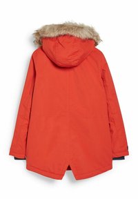 Pomarańczowa parka z futrzanym wykończeniem na kapturze, długimi rękawami i lekko przedłużonym tyłem. Wykonana z gładkiego, trwałego materiału.