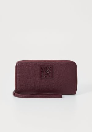 Burgundy leather wallet with embossed logo, textured surface, zip closure, and wrist strap. Rectangular shape with smooth edges.