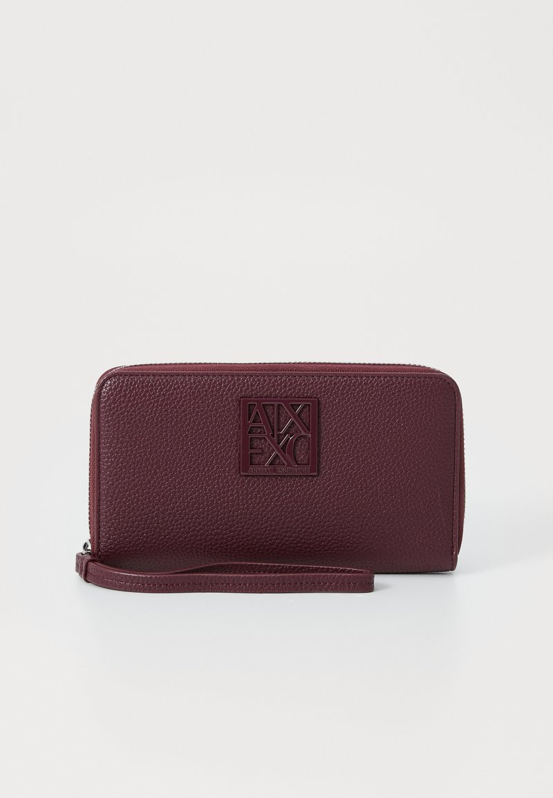 Burgundy leather wallet with embossed logo, textured surface, zip closure, and wrist strap. Rectangular shape with smooth edges.