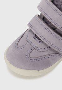 Lila Wildleder-Sneaker mit drei Klettverschlüssen, runder Zehenpartie und weißer Gummisohle. Die Nähte betonen die Textur des Designs.