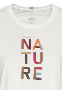 Hvid bomulds t-shirt med rund hals. Har teksten "EMPOWERED BY NATURE" i multikolor, geometriske bogstaver. Størrelse S mærket er synligt.