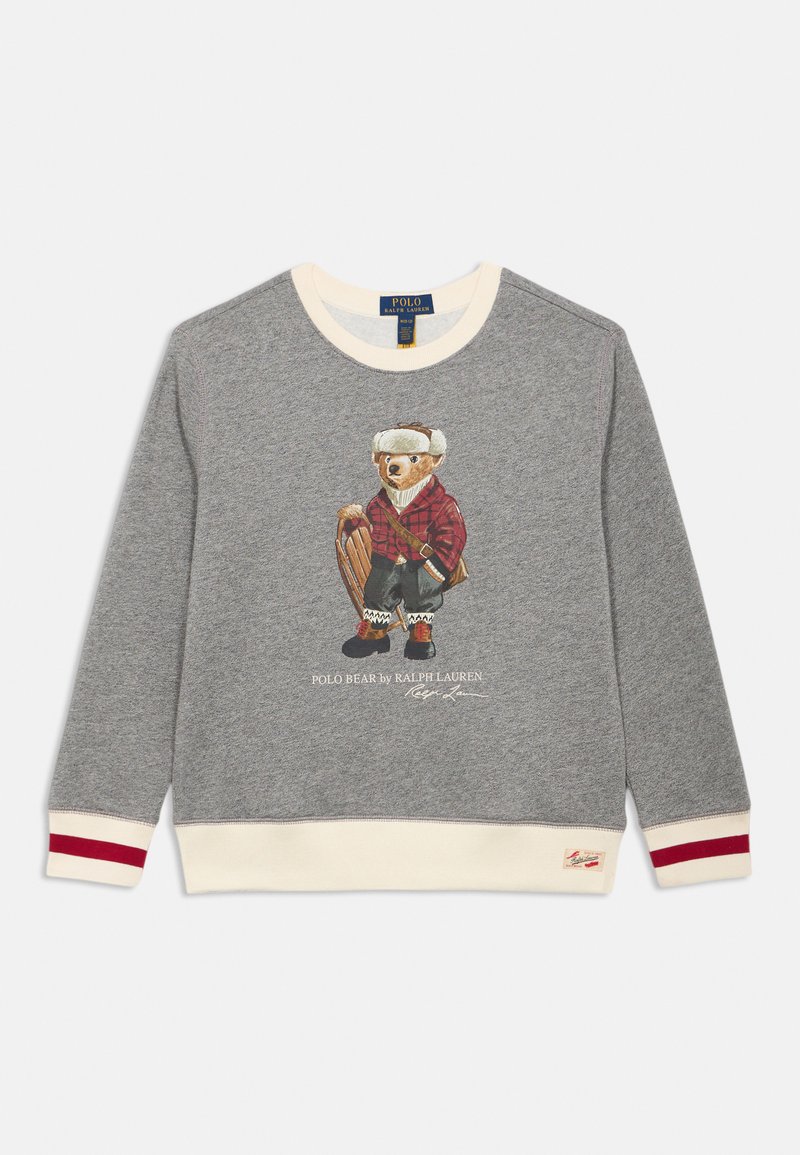 Pelēka sporta kapuce ar krēmbaltiem un sarkaniem svītrainiem ectiem, kurā attēlots lācis ziemas apģērbā, kas tur rokās ragaviņas. Teksts "Polo Bear by Ralph Lauren".