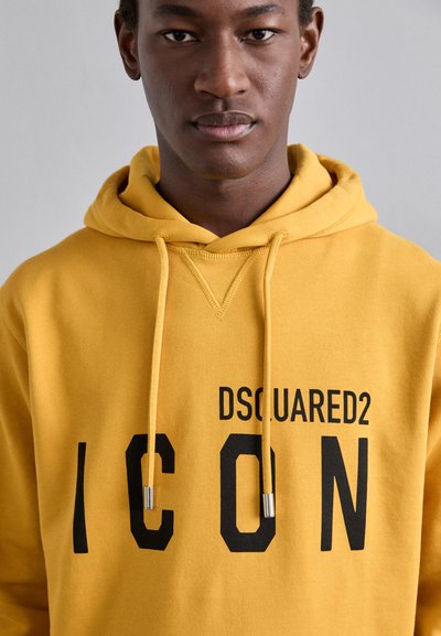 Felpa gialla in cotone con stampa frontale. Presenta un cappuccio con cordino, tasca a marsupio e il testo bold nero "DSQUARED2 ICON".