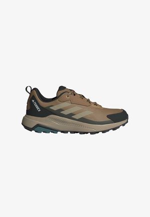 Brown athletic shoes with mesh and synthetic material, featuring a gray and black design, textured sole, and green accent on the bottom.