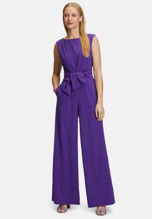 Purple jumpsuit with a fitted bodice and wide-leg design. Features a knotted waist detail and deep side pockets. Smooth fabric texture.