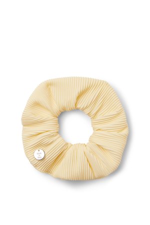Coletero de tela plisada color crema con una pequeña etiqueta metálica redonda grabada con "Made in Italy" sobre fondo blanco.