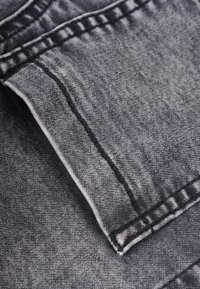 Primer plano de tela de mezclilla gris doblada que muestra las costuras detalladas y la textura del material.