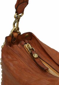 Bruine leren handtas met messing hardware, voorzien van een ritssluiting, een gestructureerd oppervlak en decoratieve studs langs de rand.