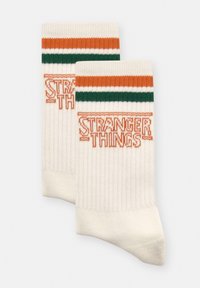 Białe bawełniane skarpety z pomarańczowymi i zielonymi paskami na górze oraz napisem "STRANGER THINGS" wyplecionym na pomarańczowo z przodu. Struktura prążkowana.