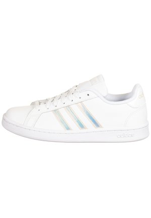 Baskets basses blanches Adidas avec trois bandes irisées, lacets, et logo embossé sur la semelle en caoutchouc et la languette du talon.