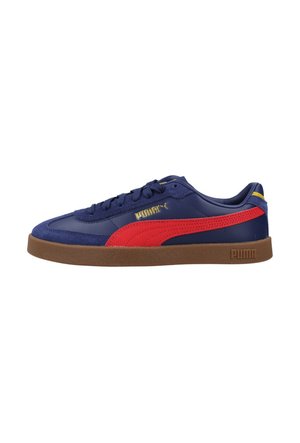 Zapatilla Puma azul marino con franja roja, suela de goma marrón, logo dorado de Puma en el lateral y diseño de corte bajo.