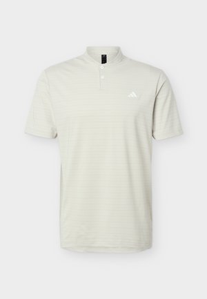 Polo beige clair à manches courtes avec une patte à deux boutons et un petit logo blanc sur le côté gauche de la poitrine, sur un fond uni.