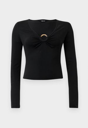 Haut noir à manches longues avec un décolleté en V, doté de tissu froncé au niveau de la poitrine et d'un accent métallique rond au centre. Matière douce et extensible.