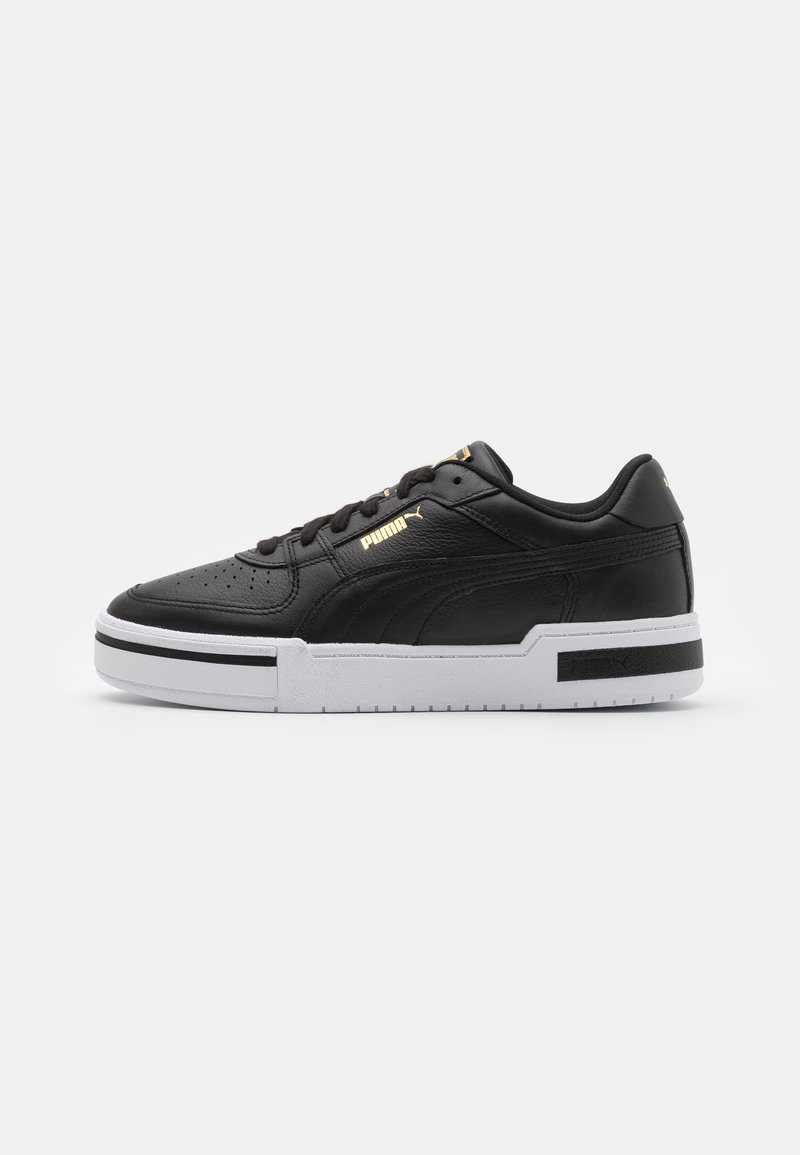 Black leather sneaker with white midsole, perforated toe, gold logo detail, padded collar, and contrasting black accents on the side.