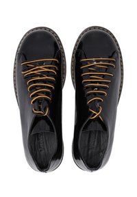 Zwarte gepatineerde leren schoenen met een ronde neus, voorzien van bruine veters en zichtbare stiksels langs de zool. Open ontwerp aan de zijkanten.