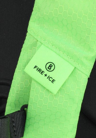 Zeleni tkanina s heksagonalnim vzorcem in prišito etiketo z napisom "FIRE+ICE," pritrjena na črno zanko.