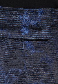 Stickad kjol i mörkblått med strukturerade ränder, med subtila glittrande accenter och en ficka med dragkedja på baksidan.