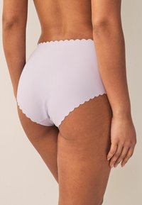 Lila sömlös underkläder med en scallop-mönstrad midja och en mjuk textur, designad för komfort och minimal synlighet under kläder.