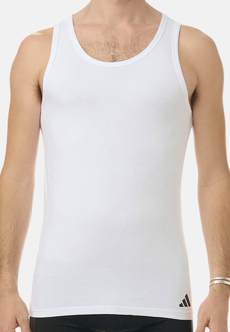 Vit ärmlös linne i mjukt bomullsmaterial. Har en rund halsringning och en liten svart logotyp i det nedre vänstra hörnet.