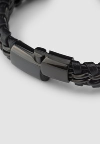 Black braided leather bracelet with a glossy black metal clasp. Features a textured design and smooth accents for a secure closure.